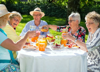 Happy elderly people sitting around the table picnicking.