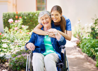 caregiver hugging the elderly woman on a wheelchair